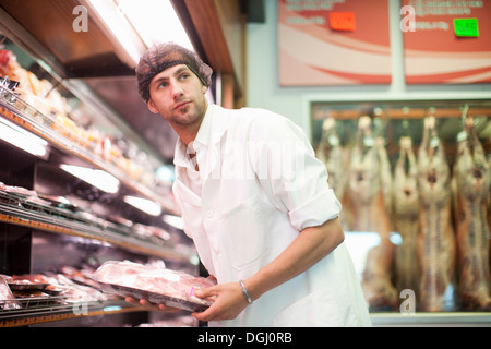 Butcher holding paquet de viande en boucherie Banque D'Images