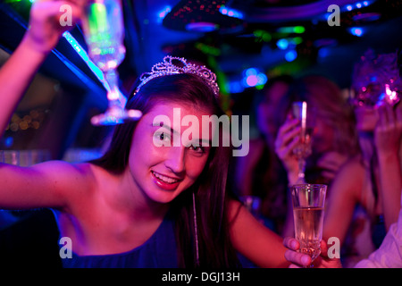 Young woman wearing tiara avec verre de vin en limousine Banque D'Images