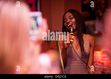 Jeune femme chantant avec microphone Banque D'Images