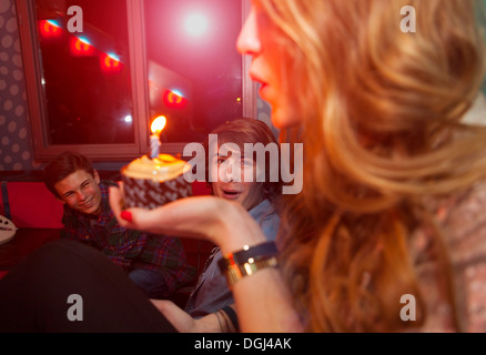 Teenage girl blowing out bougie sur le gâteau d'anniversaire Banque D'Images