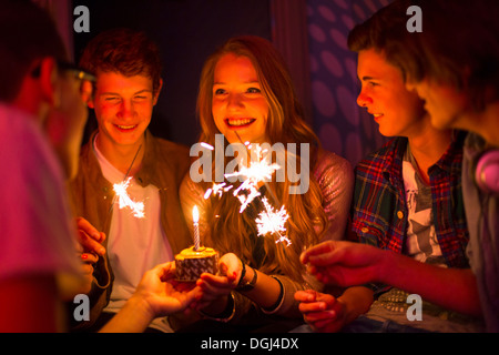 Groupe d'adolescents assis autour du gâteau d'anniversaire avec des cierges Banque D'Images