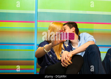 Jeune couple taking self portrait photograph of kiss Banque D'Images