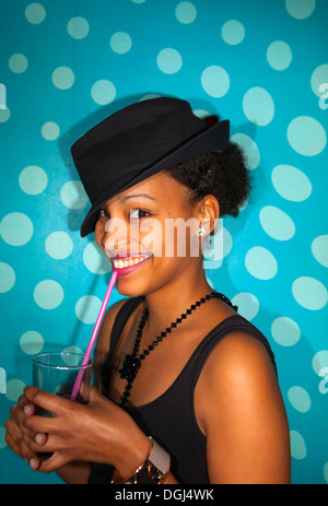 Portrait of young adult woman with mixed race ethnie smiling, verre à boire avec de la paille Banque D'Images
