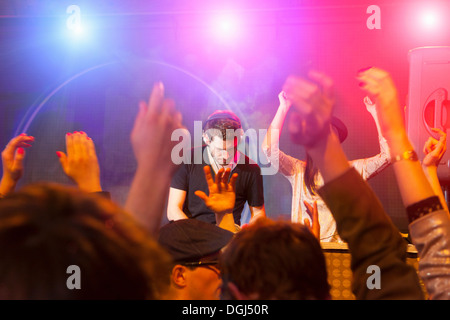 Disc Jockey entouré par les bras levés Banque D'Images