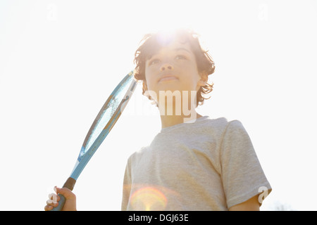 Boy holding up raquette de tennis Banque D'Images