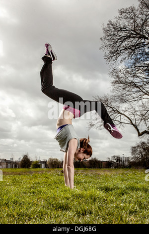 Woman doing handstand avec jambes écartées Banque D'Images