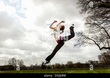 Femme sautant dans les airs avec une jambe repliée Banque D'Images