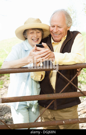 Senior couple smiling at message on mobile phone Banque D'Images