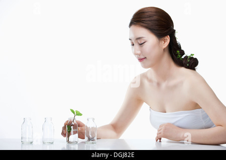 Une femme posant avec une feuille dans un vase de verre Banque D'Images