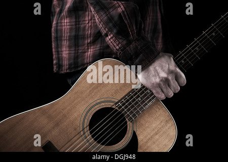 Un homme tenant une guitare acoustique. Banque D'Images