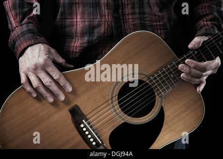 Un homme tenant une guitare acoustique. Banque D'Images