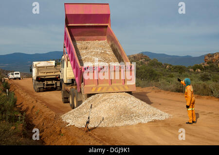 Déchargement de camion de gravier sur une rue, la construction de routes dans la région de Cederberg à Clanwilliam, Western Cape, Afrique du Sud Banque D'Images