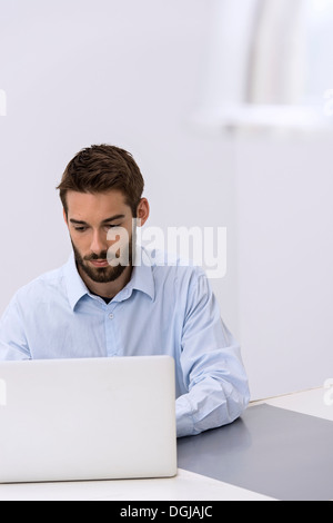 Jeune homme assis derrière laptop in office