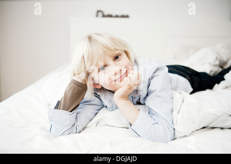 Portrait of young boy lying on bed Banque D'Images