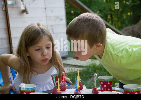 Frère et sœur blowing out birthday candles Banque D'Images