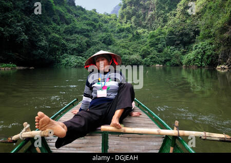 Woman rowing avec pieds, près de Ninh Binh, sur le chemin le long de la rivière pour les grottes de Trung Anh, sécheresse de la Baie d'Halong, Vietnam Banque D'Images