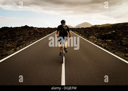 Homme randonnée cycliste sur route, Lanzarote Banque D'Images