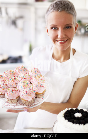 Portrait of woman holding hand made cupcakes Banque D'Images