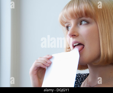 Portrait de femme à la blonde bob licking envelope Banque D'Images