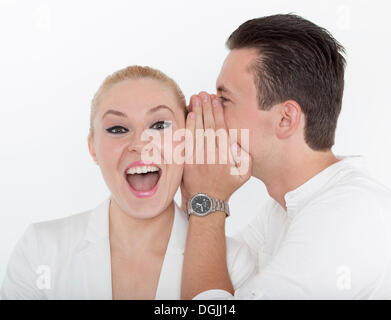 Jeune homme murmurer quelque chose à l'oreille de son jeune partenaire, elle reçoit avec joie, image symbolique de bonnes nouvelles Banque D'Images