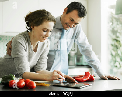 Businessman et épouse using digital tablet in kitchen Banque D'Images
