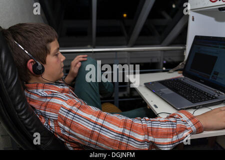 Garçon, 12 ans, à l'écoute de la musique d'internet sur un ordinateur portable Banque D'Images