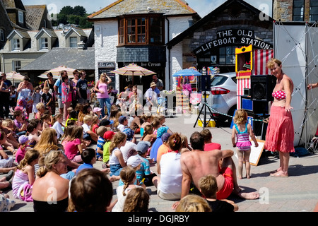 Les adultes et les enfants à regarder un Punch and Judy show sur le front de mer de Looe. Banque D'Images