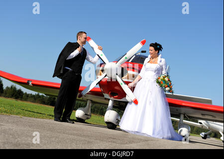 Les jeunes couples nuptiales posant devant un avion à hélice Banque D'Images