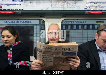 Un homme d'affaires la lecture du Financial Times de Londres sur un train de tube. Banque D'Images