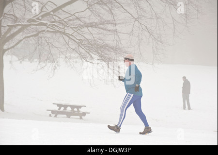 A middle aged man jogging à travers du brouillard givrant et la neige. Banque D'Images