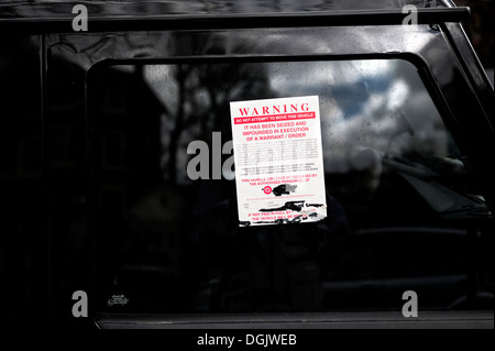 Un avertissement collé sur la fenêtre d'un véhicule en stationnement illégal. Banque D'Images