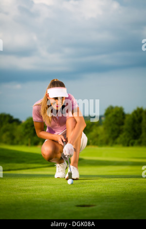 Femelle jeune joueur de golf sur le cours visant à mettre Banque D'Images