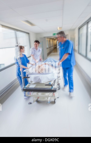 Motion blurred photo d'une femme senior patient sur civière ou gurney poussés en pleine vitesse dans un couloir de l'hôpital Banque D'Images