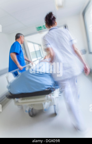 Motion blurred photo d'une femme senior patient sur civière ou gurney poussés en pleine vitesse dans un couloir de l'hôpital Banque D'Images