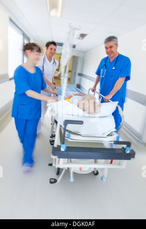 Motion blurred photo d'une femme senior patient sur civière ou gurney poussés en pleine vitesse dans un couloir de l'hôpital Banque D'Images