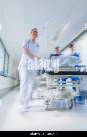 Motion photographie floue patient sur civière ou gurney poussés en pleine vitesse dans un couloir de l'hôpital par les médecins et infirmières Banque D'Images