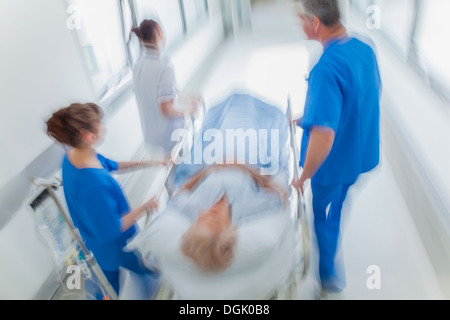 Motion blurred photo d'une femme senior patient sur civière ou gurney poussés en pleine vitesse dans un couloir de l'hôpital Banque D'Images