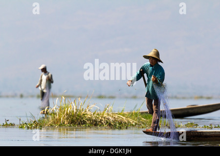 L'aviron et jambe Fisherman casting ses filets sur le lac Inle au Myanmar. Banque D'Images