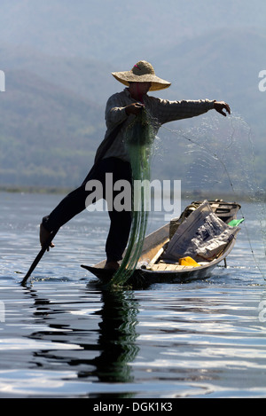 L'aviron et jambe Fisherman casting ses filets sur le lac Inle au Myanmar. Banque D'Images