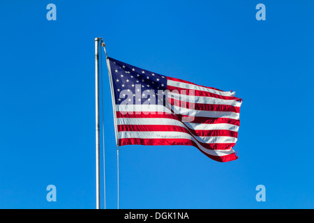 Un drapeau américain dans le vent sur un mât contre un ciel bleu. Banque D'Images