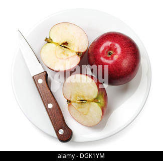 Pomme entière, coupées en deux et un couteau sur une plaque on white Banque D'Images