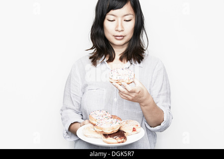 Pregnant woman holding plate of donuts Banque D'Images