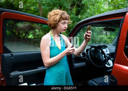 Femme dans la forêt à la recherche de miroir compact Banque D'Images