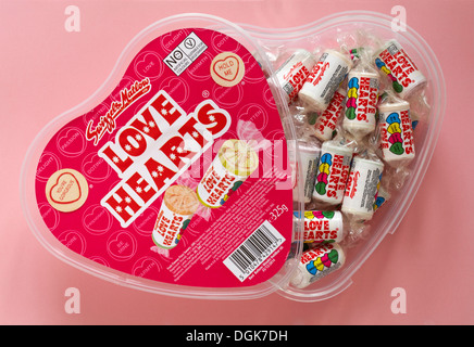 Contenant en plastique en forme de coeur de Swizzels amour coeur bonbons bonbons bonbons bonbons bonbons avec couvercle éteint pour montrer le contenu isolé sur fond rose - coeur de loveheart Banque D'Images