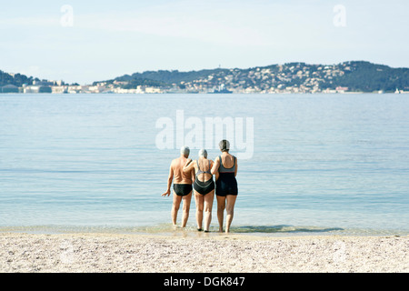 Trois amis marchant dans la mer, vue arrière Banque D'Images