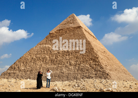 Une femme égyptienne photographies un touriste à l'Khafré pyramide de Gizeh. Banque D'Images