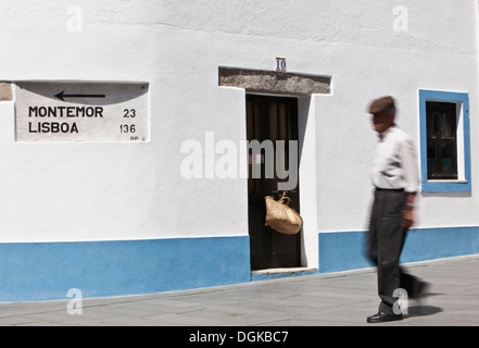 Un vieil homme marche local passé un signe à Lisbonne sur le mur d'une traditionnelle maison garni de bleu. Banque D'Images