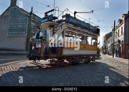 Un conducteur de tramway conduit un ancien tramway Transport préservé Newcastle Numéro 114, construit en 1901 par le biais de rues pavées de 'La Ville' dans Beamish Musée Vivant, Stanley, County Durham Banque D'Images