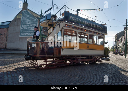 Un conducteur de tramway conduit un ancien tramway Transport préservé Newcastle Numéro 114, construit en 1901 par le biais de rues pavées de 'La Ville' dans Beamish Musée Vivant, Stanley, comté de Durham. Banque D'Images