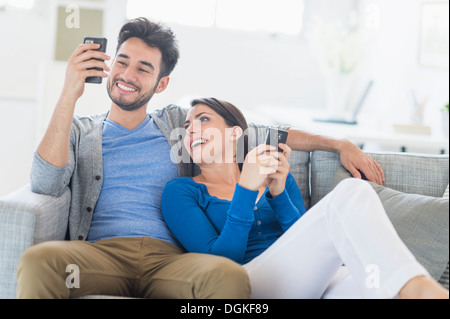 Couple relaxing on sofa with cell phones Banque D'Images